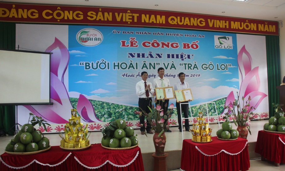 Ông Trần Đình Chương, Phó Giám đốc Sở KH&CN (bìa trái) trao hai Giấy chứng nhận nhãn hiệu cho các đại diện chủ sở hữu sản phẩm.